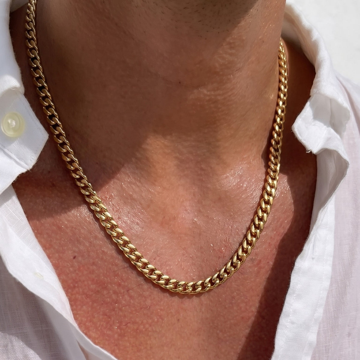 5mm gold cuban chain necklace worn by a person with a white shirt.